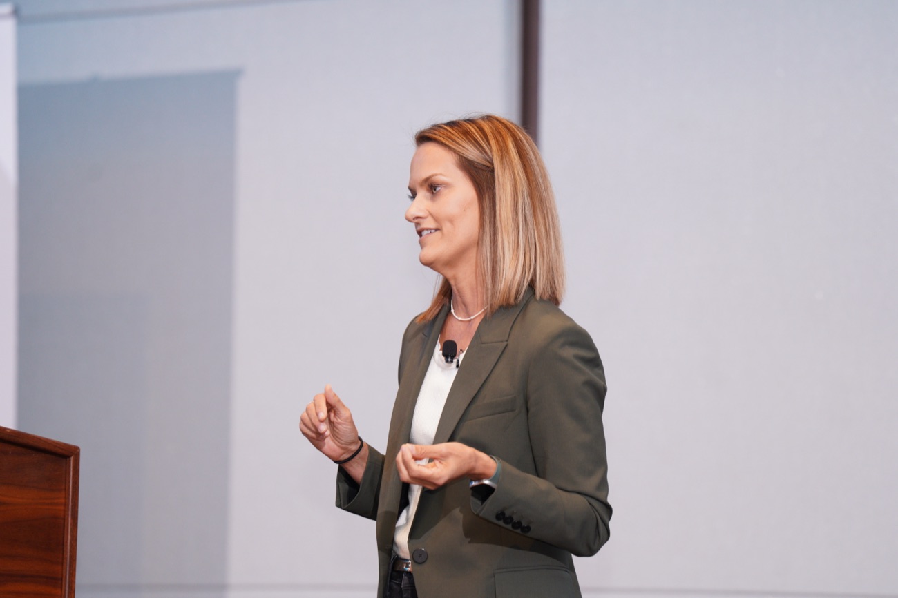 Angie Carel mid-keynote, gesturing to the audience