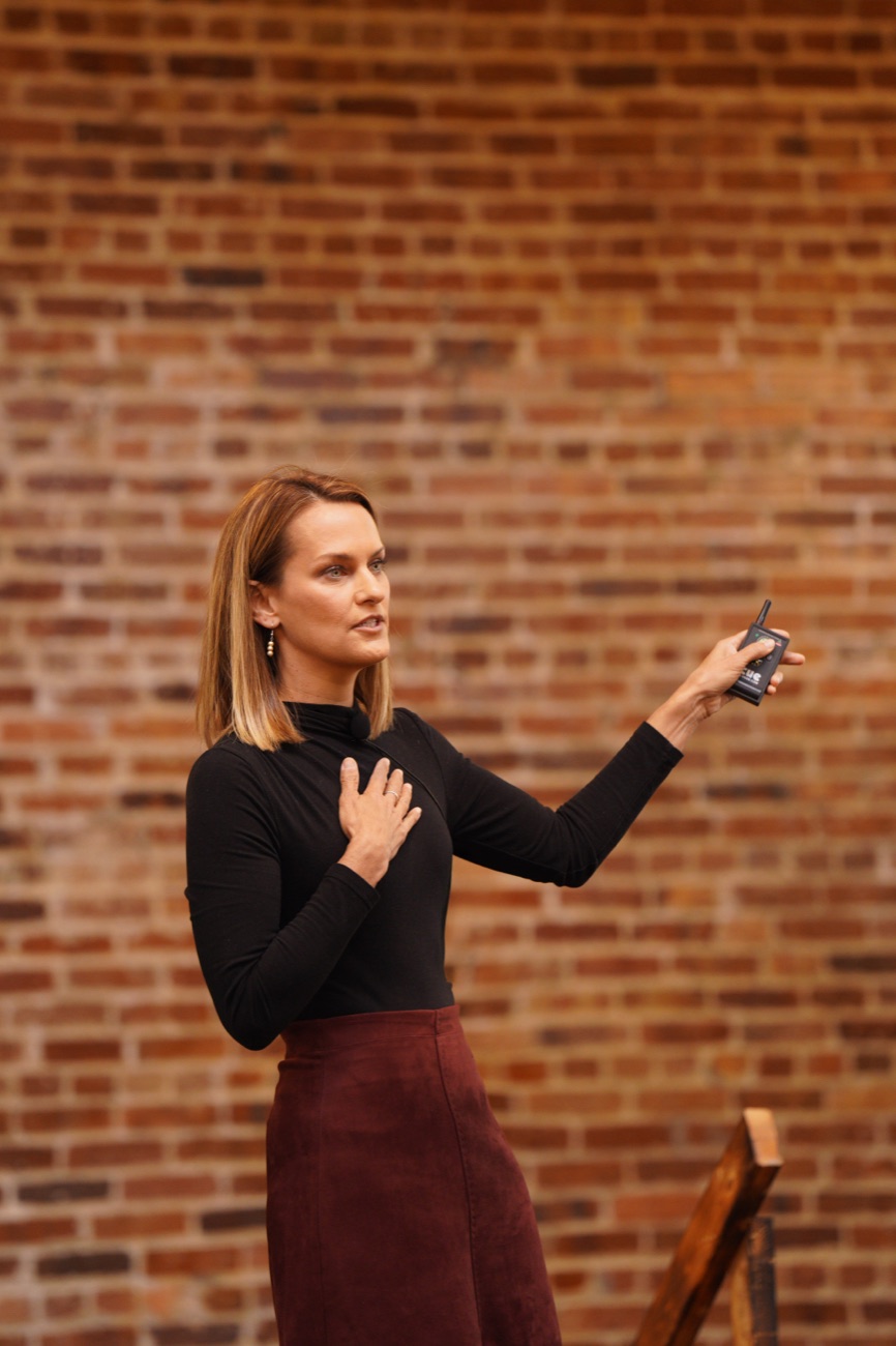 Angie Carel presenting against a brick backdrop